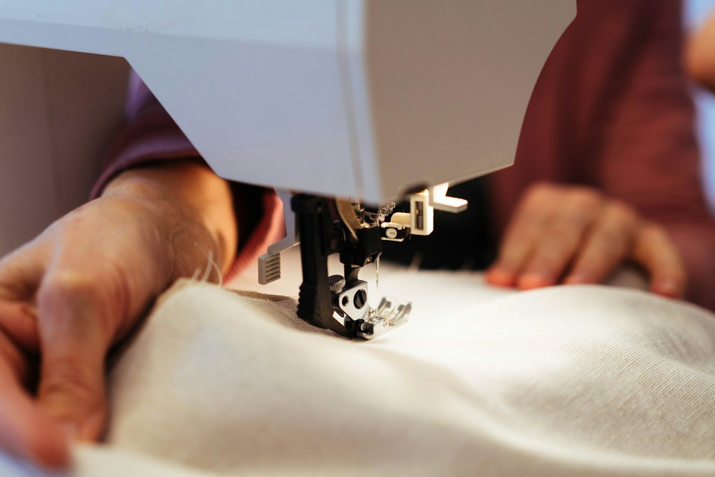 Hands guiding fabric through a sewing machine